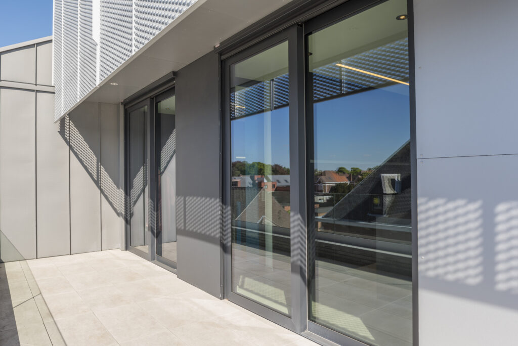 Moderne aluminium schuiframen op maat met strakke afwerking en grote glaspartijen, gerealiseerd door Bruvo.