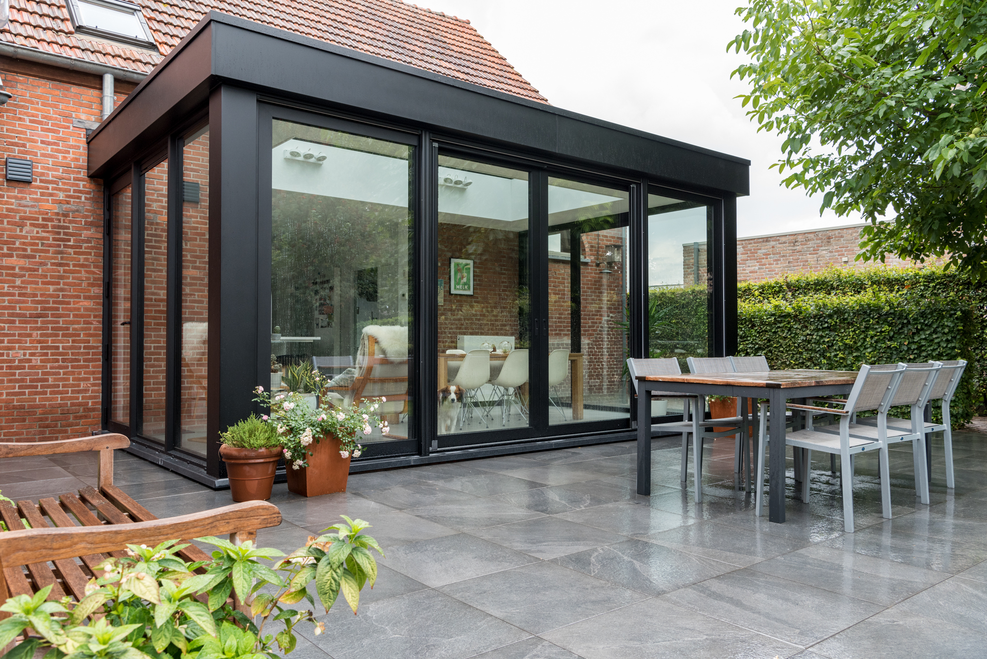Zonovergoten moderne leefveranda met antraciet raamprofielen en een plat dak.