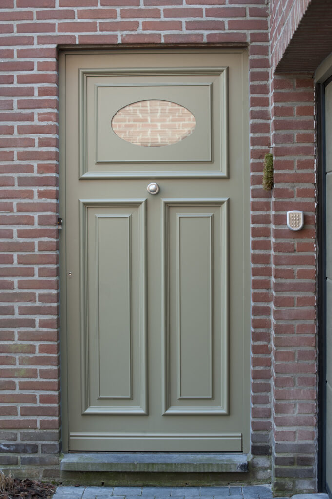 Klassieke aluminium voordeur in zachte groene tint met ovaal glasraam, op maat gemaakt door Bruvo voor een stijlvolle en duurzame afwerking van de gevel.