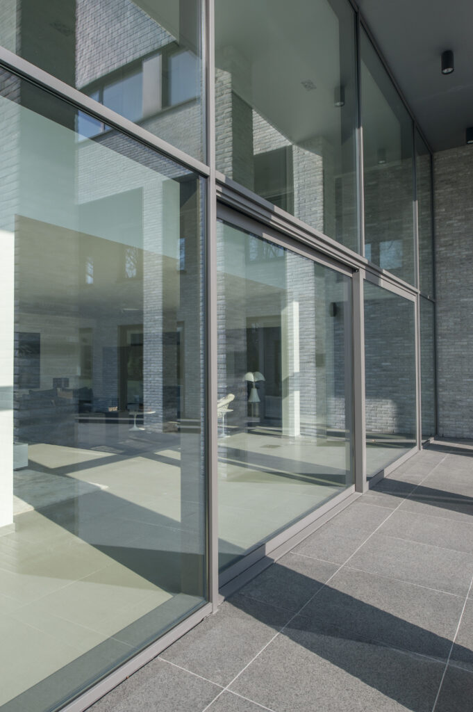 Moderne woning met hoge aluminium ramen en schuiframen in grijze profielen, geplaatst door Bruvo.
