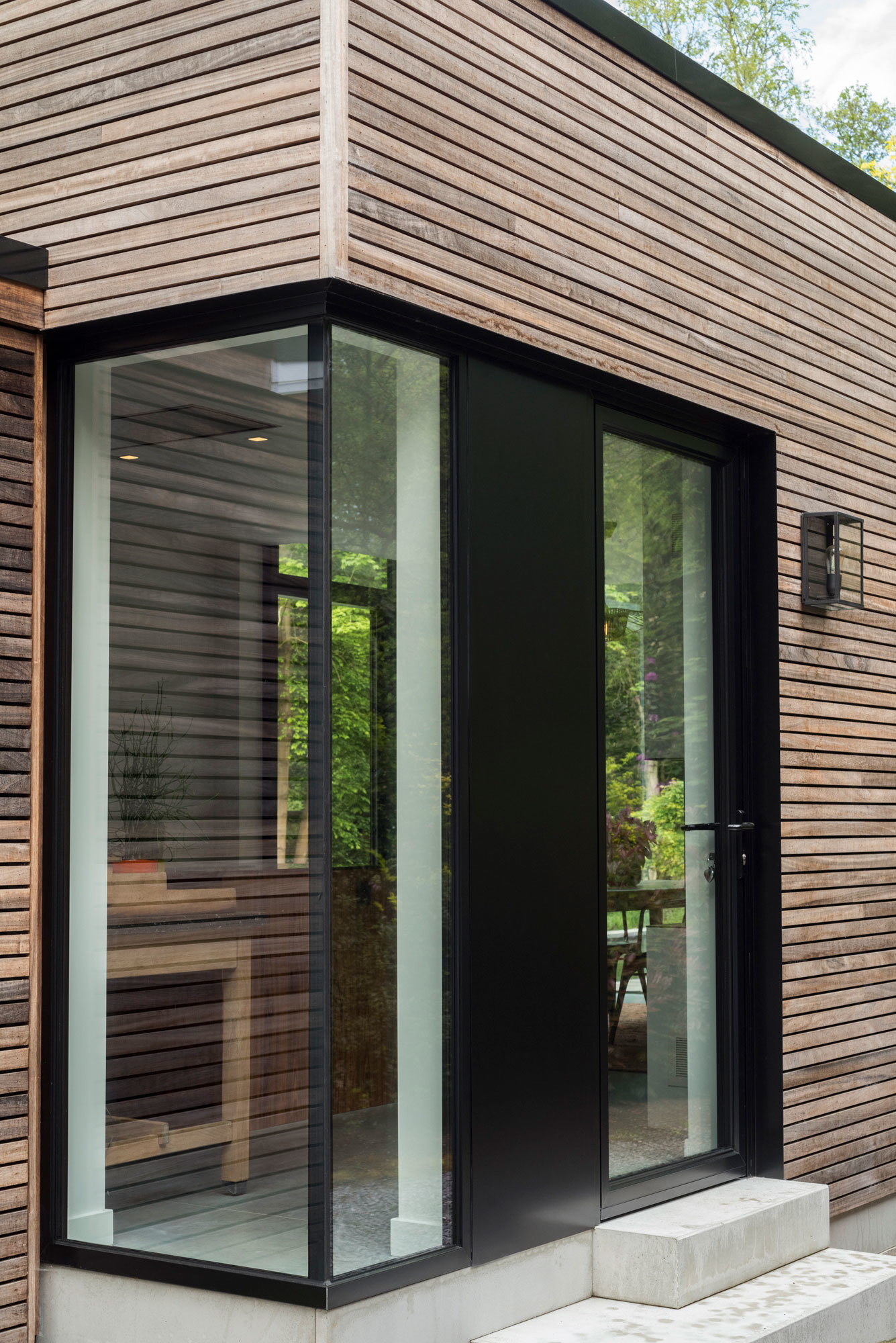 Moderne aluminium schuifdeur met grote glaspartij in houten gevel