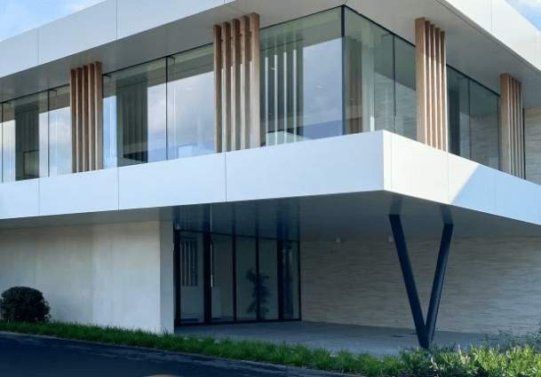 Moderne woning met grote aluminium ramen en glasgevel van Bruynseels-Vochten, strak architecturaal ontwerp met houten accentlatten en energiezuinige afwerking.