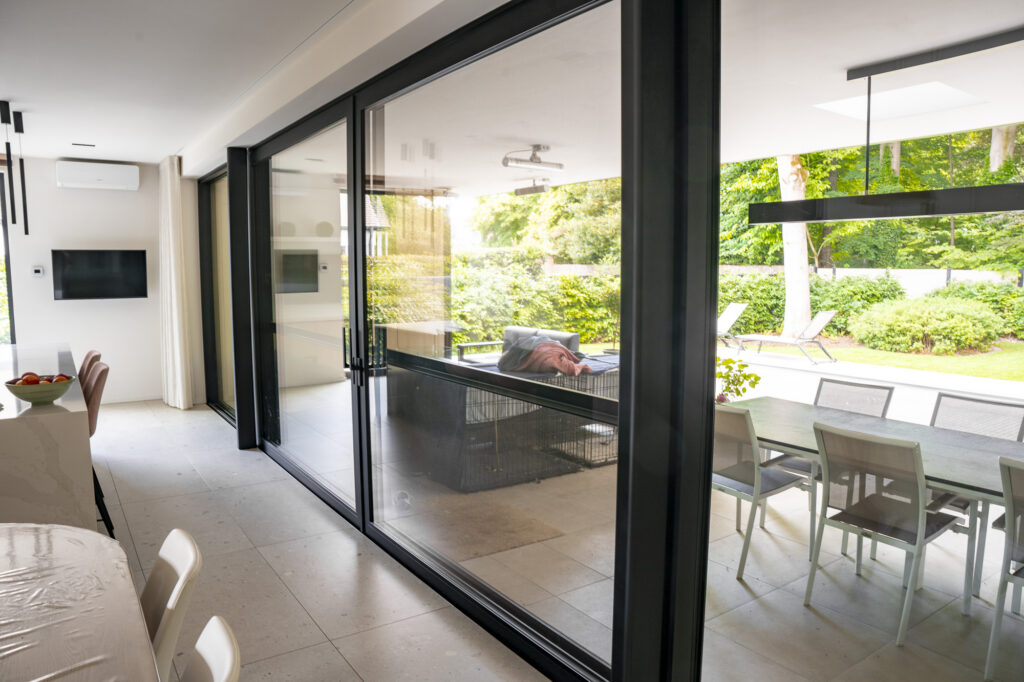 Aluminium schuiframen van Bruvo die de eetruimte verbinden met het terras en de tuin.