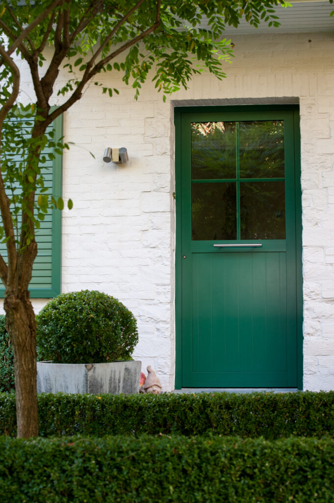 Groene aluminium voordeur met glaspartij in landelijke woning met witte gevel, ontworpen en geplaatst door Bruvo voor een frisse en karaktervolle inkom.