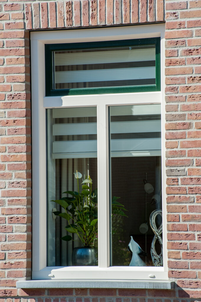 Aluminium raam met wit profiel en bovenlicht in een klassieke bakstenen gevel, geplaatst door Bruvo.