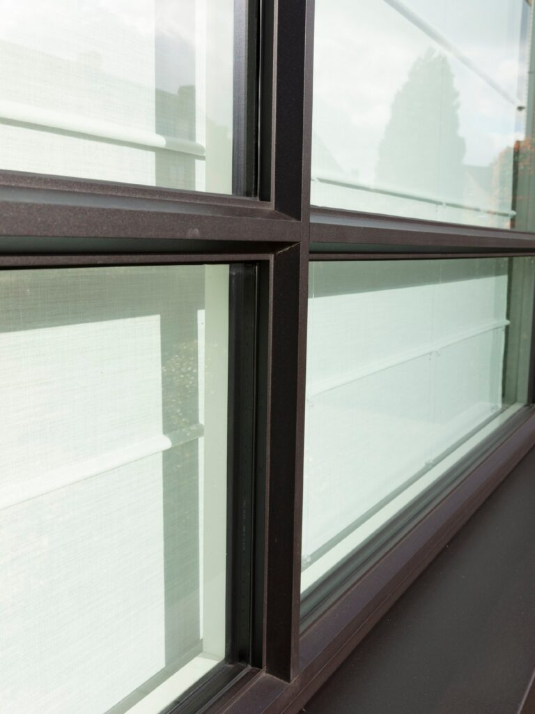 Detail van zwart aluminium raamprofiel met strakke roedes en grote glaspartijen, ontworpen voor maximale lichtinval en een moderne architecturale uitstraling.