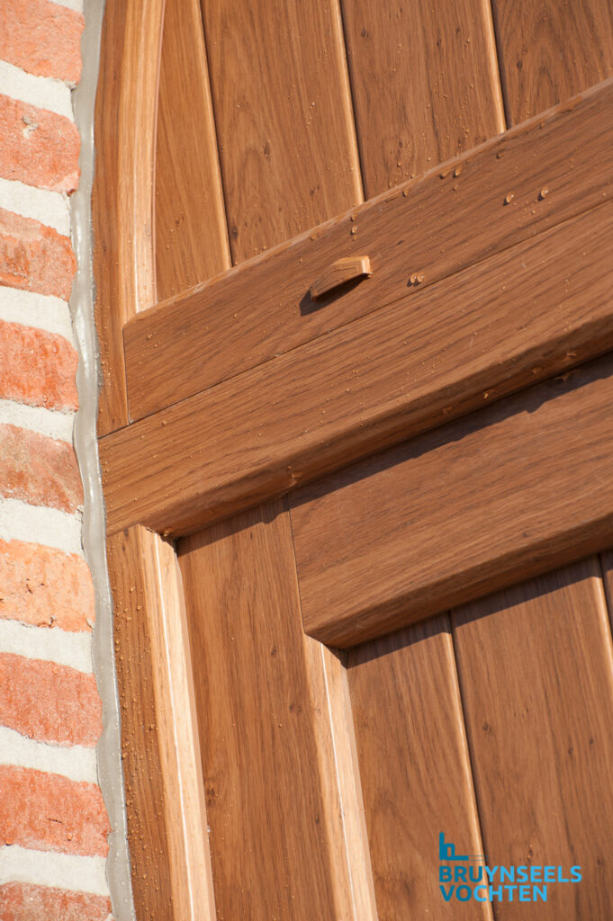 Detail van een Softline 70 deur in houtstructuur met verticale panelen en natuurgetrouwe houtnerf, geplaatst tegen een gevel met baksteen.