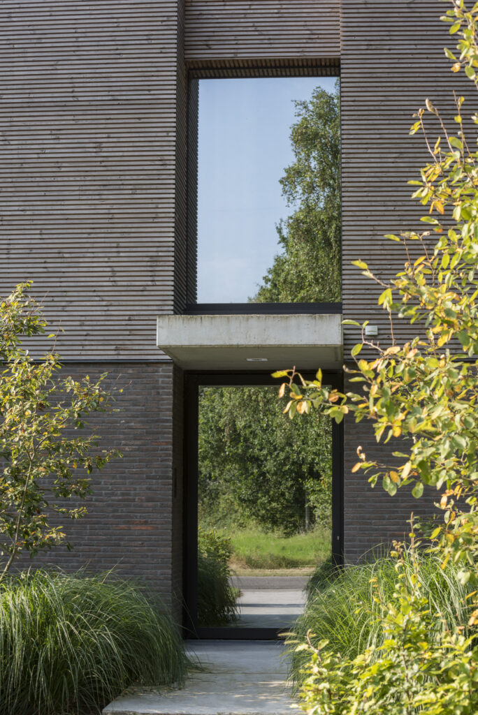 Moderne woning met hoog aluminium raam en houten gevelbekleding, gerealiseerd door Bruvo.