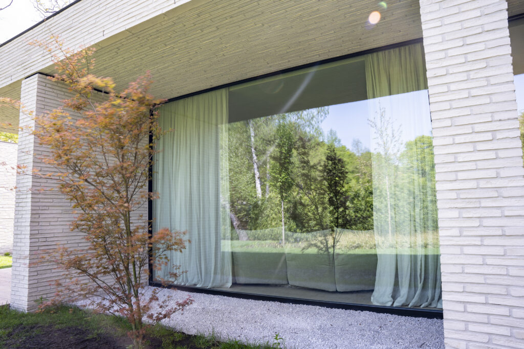 Moderne woning met groot aluminium raam en witte gevelsteen, gerealiseerd door Bruvo.