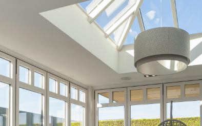 Lichte veranda met wit aluminium schrijnwerk en groot dakraam dat overvloedig natuurlijk licht binnenlaat