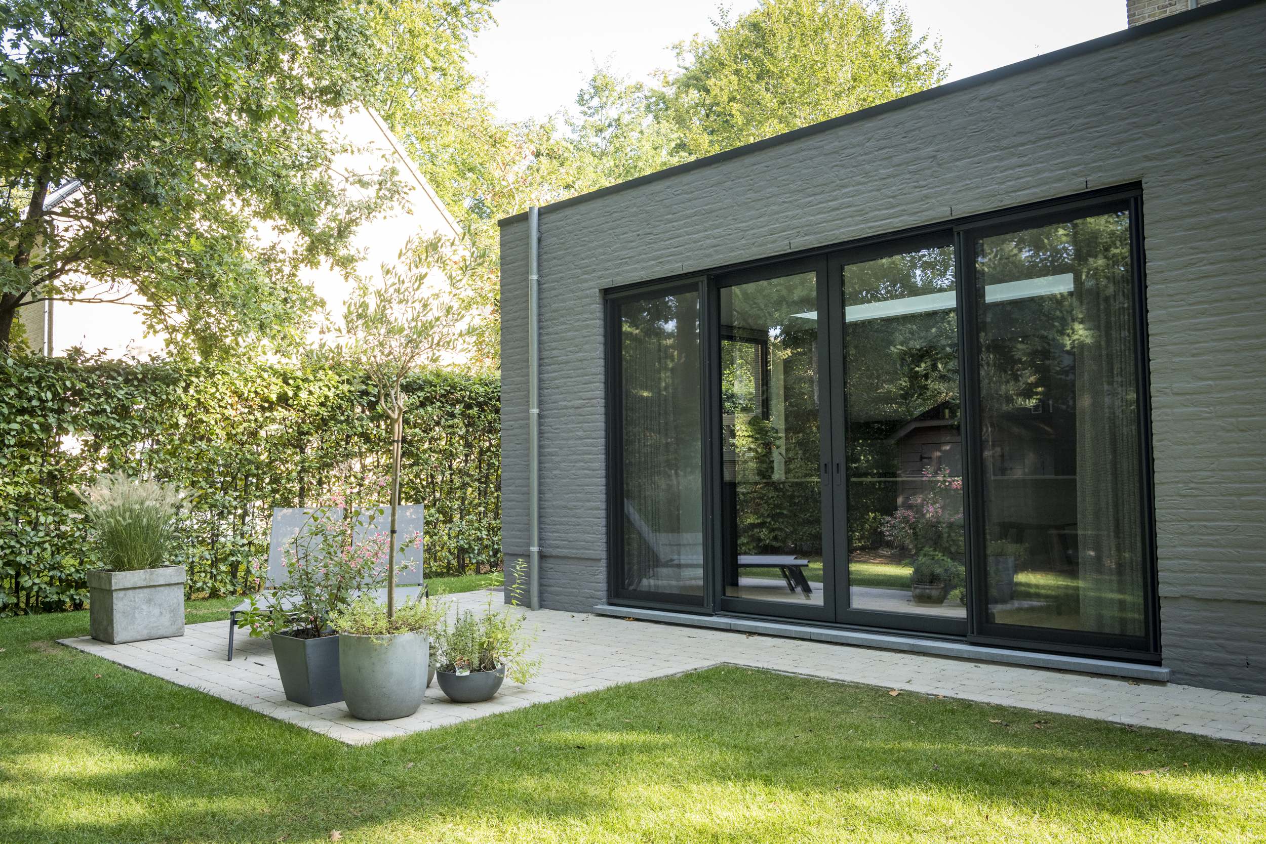 Strakke architecturale uitbouw met kamerhoge zwarte aluminium ramen – realisatie door Bruynseels-Vochten.